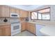 Galley kitchen with wood cabinets, white appliances, and a window overlooking the backyard at 502 Hilldale Rd, Brandon, FL 33510