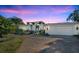 White two-story house with a three-car garage and landscaped yard at dusk at 105 Estado Ne Way, St Petersburg, FL 33704