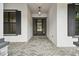 Inviting front entrance with dark gray door, gray shutters, and a brick walkway at 19504 Sheltered Hill Dr, Brooksville, FL 34601