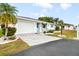 White brick home with teal accents, a paved driveway, and lush landscaping at 708 Rutgers Pl, Sun City Center, FL 33573