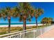 Scenic view of white sand beach and ocean through palm trees from complex balcony at 1390 Gulf Blvd # 1204, Clearwater, FL 33767