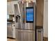 Stainless steel refrigerator with a built-in display screen, next to a stainless trash can at 14492 Tanglewood N Dr, Largo, FL 33774