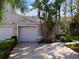 Light beige house with attached garage and tropical landscaping at 1687 Starling Drive, Tarpon Springs, FL 34689
