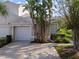 Tan house with attached garage and tropical landscaping at 1687 Starling Drive, Tarpon Springs, FL 34689