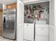 Utility closet featuring a washer, dryer, shelving, storage, and stainless-steel refrigerator at 8019 Feather Ct # C, Hudson, FL 34667