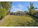 Expansive backyard featuring lush green lawn, a screened-in pool, privacy fence, and mature bamboo at 13632 Imperial Groves S Dr, Largo, FL 33774