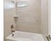 Clean, modern bathroom with white tub, tiled wall, and window for natural light at 5825 S 5Th St, Tampa, FL 33611