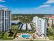 Wide view of two condos, a parking lot, and a pool surrounded by trees, under a bright sky at 2401 Bayshore Blvd # 410 & 510, Tampa, FL 33629