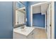 This bathroom features a vanity with a mirror, blue walls, and doorways leading to other areas at 4129 36Th N Ave, St Petersburg, FL 33713