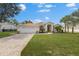 Single-story home with tile roof, two-car garage, and landscaped lawn at 8420 Maybelle Dr, Weeki Wachee, FL 34613