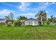 An image of the backyard showcasing the grassy area with mature trees and partial fencing at 109 San Rafael Ave, North Port, FL 34287
