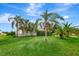Captures the home's front yard with a variety of palm trees and lush green grass at 109 San Rafael Ave, North Port, FL 34287