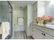 Bright bathroom featuring a glass door shower, white cabinets, drawers, and decorative pink flowers at 1430 Gulf Blvd # 204, Clearwater Beach, FL 33767