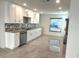 Well-lit kitchen featuring white cabinets, granite countertops, stainless steel appliances, and tile backsplash at 1906 Castle Bay Ct, Oldsmar, FL 34677