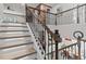 Upper view of the illuminated staircase with decorative iron railing, overlooking the living area at 19270 Briarbrook Dr, Tampa, FL 33647