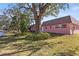 Quaint pink home features lush green lawn, mature trees, and canal views at 7075 Lafayette N, Pinellas Park, FL 33781