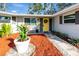 Inviting front porch boasts a bright yellow door, stone pathway, and colorful landscaping at 4151 Olive Ave, Sarasota, FL 34231