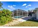 The screened-in pool features a lush green bush and well kept backyard at 11945 Carmen Ave, Dade City, FL 33525