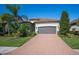 One story house with gray garage door and brick driveway. Lush landscaping and palm trees complete the look at 12241 Perennial Pl, Bradenton, FL 34211