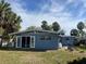 Back exterior view of a light blue house with a spacious backyard at 3863 Belle Vista E Dr, St Pete Beach, FL 33706