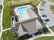 Overhead view of a rectangular community pool and an adjacent building with a metal roof and parking area at 3901 Tour Trce, Land O Lakes, FL 34638
