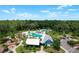 Aerial view of a neighborhood pool and clubhouse surrounded by lush trees and a bright blue sky at 3901 Tour Trce, Land O Lakes, FL 34638
