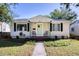 Charming light-yellow house with a green door, well-manicured lawn, and mature trees at 5219 Dr Martin Luther King Jr N St, St Petersburg, FL 33703