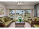 Relaxing sunroom with green sofas and wicker table, overlooking tennis courts at 12300 Vonn Rd # 9205, Largo, FL 33774