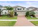 Inviting two-story home featuring a well-manicured lawn, lush landscaping, and a brick driveway leading to a two-car garage at 19757 Long Lake Ranch Blvd, Lutz, FL 33558
