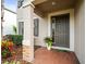 Covered front porch featuring a decorative column, brick accents, and a stylish entrance door with sidelight at 19757 Long Lake Ranch Blvd, Lutz, FL 33558