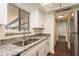 White kitchen cabinets, granite counters, and stainless steel sink at 206 Tarpon Pt, Tarpon Springs, FL 34689
