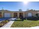 Tan single-story home with a two car garage and a landscaped yard at 7430 Buchanan Dr, Port Richey, FL 34668