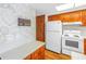 Kitchen with wood cabinets, white appliances and stone wall detail at 7430 Buchanan Dr, Port Richey, FL 34668