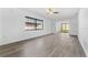Open living room featuring light grey wood-look flooring, ceiling fan, and large windows at 13250 Ridge Rd # 2-1, Largo, FL 33778