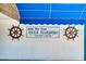 Gulf Harbors Yacht Club sign with ship's wheels on a white wall under a blue awning at 3960 Headsail Dr, New Port Richey, FL 34652
