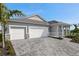 Exterior view of a house featuring a two-car garage, stone accents, and a paved driveway at 18424 Vista Park Ter, Venice, FL 34293