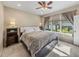 Cozy bedroom features a plush bed, ceiling fan, and a bright window overlooking the landscaped yard at 8916 Arabella Ln, Seminole, FL 33777