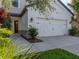 Home's white two-car garage with updated carriage doors, green lawn and landscaped beds at 8916 Arabella Ln, Seminole, FL 33777