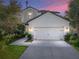 Twilight view of the home's exterior featuring a two-car garage and manicured landscaping at 8916 Arabella Ln, Seminole, FL 33777