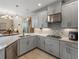 Kitchen with gray cabinets, tile backsplash, stainless steel appliances, and open to the living room at 8916 Arabella Ln, Seminole, FL 33777