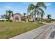 Landscaped home exterior with palm trees and a curved walkway at 2217 Platinum Dr, Sun City Center, FL 33573