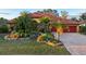 House front with lush landscaping and red garage doors at 3921 Mimosa Pl, Palm Harbor, FL 34685
