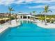 Community pool featuring crystal clear water, sun umbrellas, and a clubhouse in the background at 12241 Meditation Trl, Venice, FL 34293
