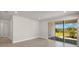 Bright, minimalist living area with tile floors and sliding glass doors to a patio at 12241 Meditation Trl, Venice, FL 34293
