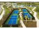 Aerial view of community pickleball courts, lush landscaping, and nearby community pool at 12241 Meditation Trl, Venice, FL 34293