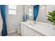 Clean bathroom with white vanity, quartz countertop, and blue curtains at 31526 Ancient Sage Rd, Wesley Chapel, FL 33545