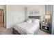 Well-lit bedroom with gray upholstered bed, nightstand, and double doors at 31526 Ancient Sage Rd, Wesley Chapel, FL 33545