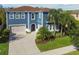 Two-story blue home with a brick-red roof, large garage and palm trees in the front yard at 4383 Ortona Ln, Wesley Chapel, FL 33543