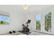 Bright home gym with Peloton bike, weights, and French doors leading to a balcony at 4383 Ortona Ln, Wesley Chapel, FL 33543