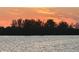 Stunning sunset over calm water with lush trees in the background at 5676 Oakhurst Dr, Seminole, FL 33772